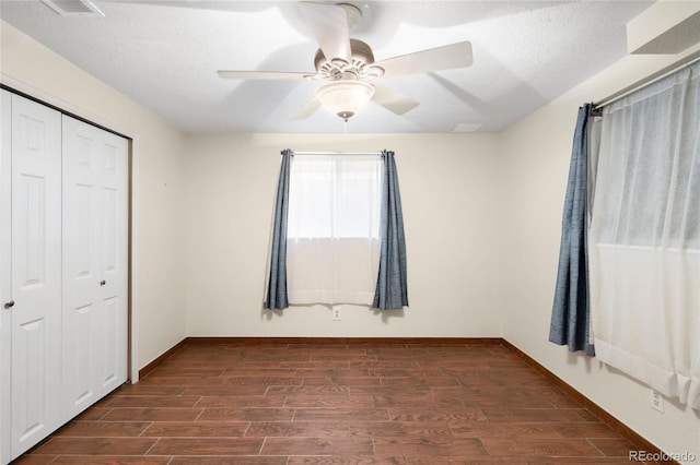 unfurnished bedroom with dark wood finished floors, a closet, baseboards, a ceiling fan, and a textured ceiling