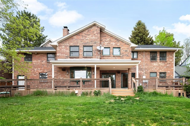 back of property with brick siding, a chimney, and a lawn