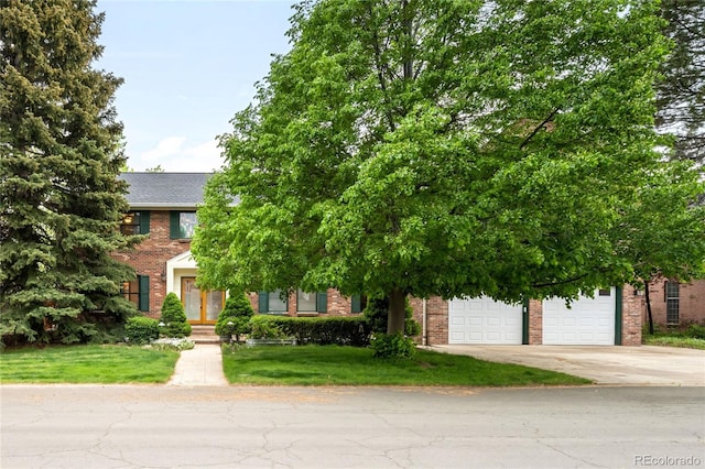 view of property hidden behind natural elements with concrete driveway, brick siding, and a front lawn