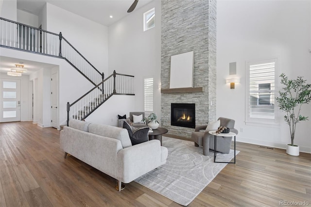 81 Simmental Loop, Castle Rock, CO 80104 - living room featuring a towering ceiling, wood finished floors, stairway, a ceiling fan, and a stone fireplace