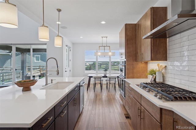 81 Simmental Loop, Castle Rock, CO 80104 - kitchen with wall chimney exhaust hood, stainless steel appliances, light wood-type flooring, light countertops, and backsplash