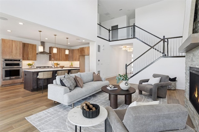 81 Simmental Loop, Castle Rock, CO 80104 - living area featuring stairway, light wood-style flooring, a stone fireplace, a towering ceiling, and recessed lighting