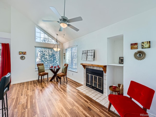 living area featuring a healthy amount of sunlight, ceiling fan, a fireplace, and wood finished floors