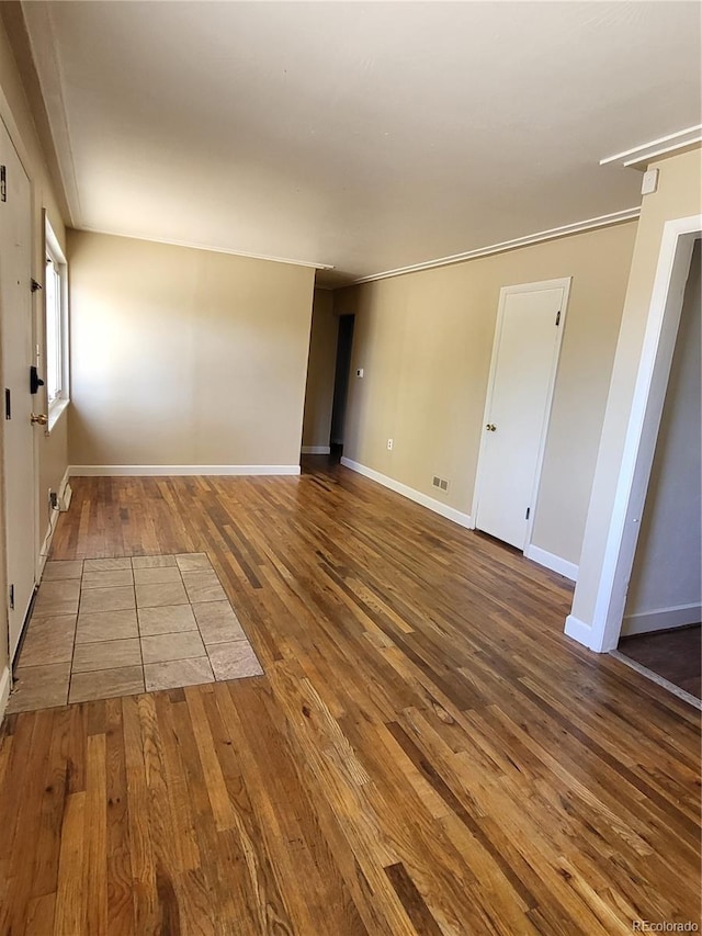 empty room featuring ornamental molding and hardwood / wood-style floors