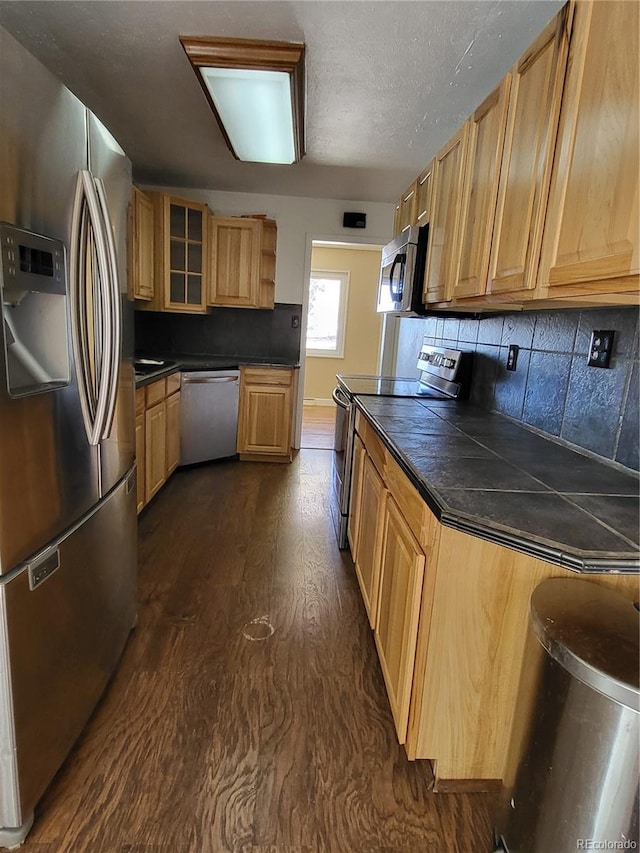 kitchen featuring tasteful backsplash, stainless steel appliances, light brown cabinetry, and dark hardwood / wood-style flooring