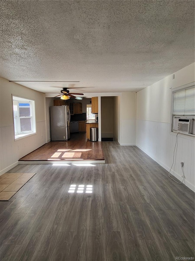 unfurnished living room featuring ceiling fan, a textured ceiling, cooling unit, and dark hardwood / wood-style floors