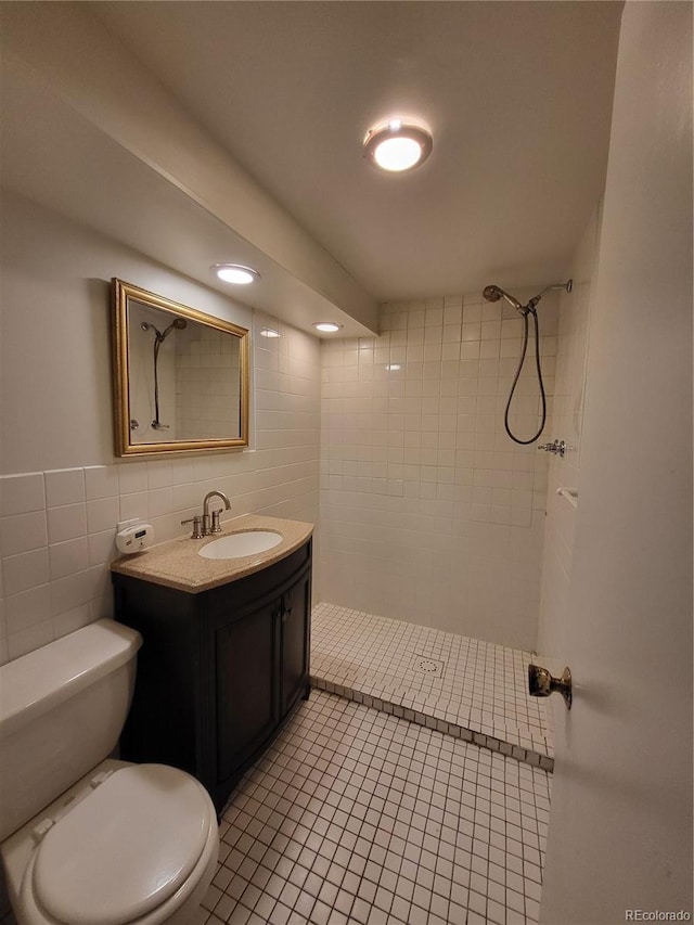 bathroom featuring toilet, vanity, tile walls, and tiled shower