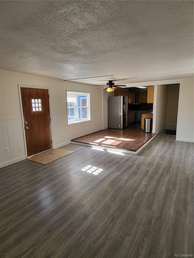 unfurnished living room with dark hardwood / wood-style floors, a textured ceiling, and ceiling fan