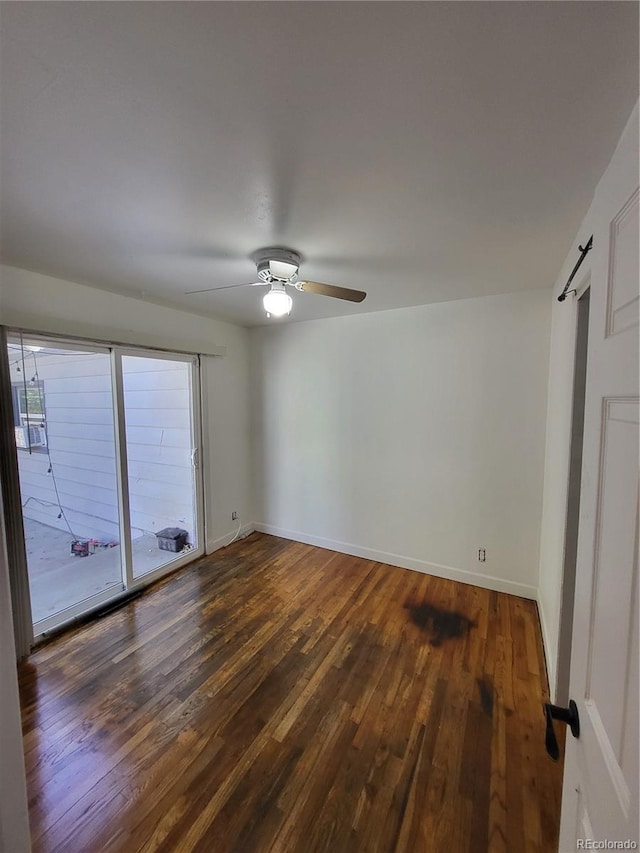 spare room featuring dark hardwood / wood-style floors, a barn door, a healthy amount of sunlight, and ceiling fan