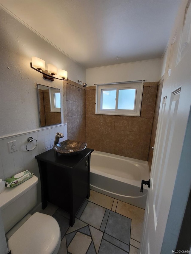 full bathroom featuring tile walls, toilet, vanity, tiled shower / bath combo, and tile patterned flooring