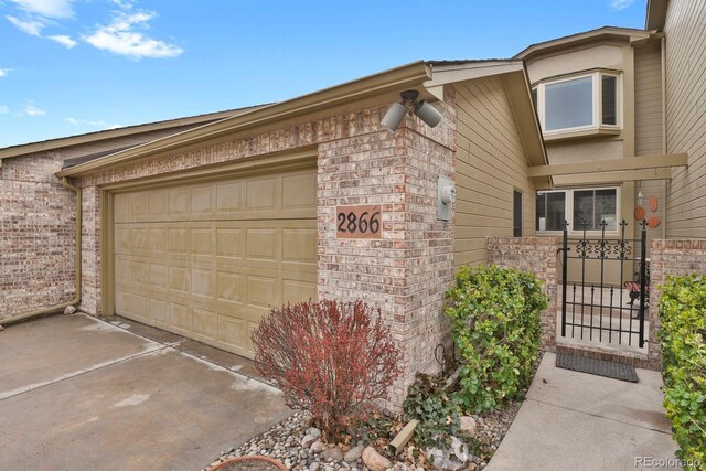 2866 Tenderfoot Hill St, Colorado Springs, CO 80906 - view of home's exterior with concrete driveway, a gate, brick siding, and a garage
