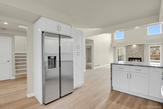 2866 Tenderfoot Hill St, Colorado Springs, CO 80906 - kitchen with white cabinets, visible vents, light stone counters, stainless steel refrigerator with ice dispenser, and a stone fireplace