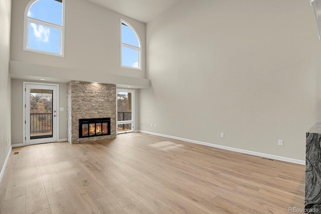 2866 Tenderfoot Hill St, Colorado Springs, CO 80906 - unfurnished living room with a stone fireplace, a towering ceiling, and light wood finished floors