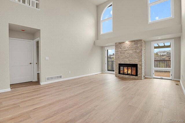 2866 Tenderfoot Hill St, Colorado Springs, CO 80906 - unfurnished living room with a fireplace, light wood-type flooring, a high ceiling, and visible vents