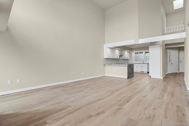 2866 Tenderfoot Hill St, Colorado Springs, CO 80906 - unfurnished living room featuring a high ceiling, visible vents, a sink, light wood-type flooring, and baseboards