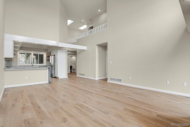2866 Tenderfoot Hill St, Colorado Springs, CO 80906 - unfurnished living room with light wood-style floors, visible vents, and a towering ceiling