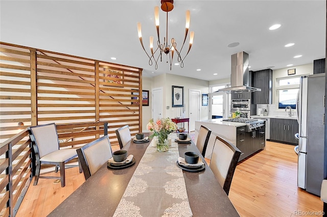 dining area with sink, a chandelier, and light hardwood / wood-style flooring