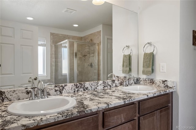 bathroom with a shower with shower door and vanity