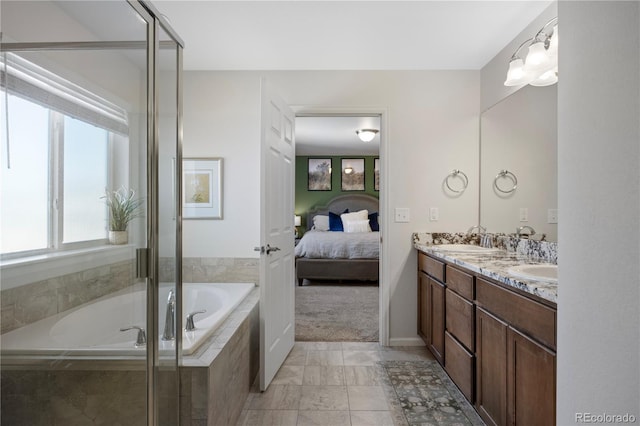 bathroom with tile patterned flooring, tiled tub, and vanity