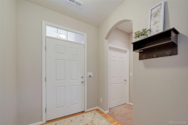 entrance foyer with visible vents, arched walkways, baseboards, and light wood-style floors