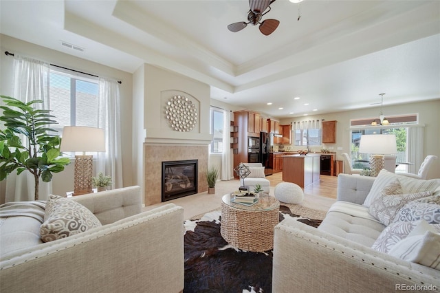 living room with ceiling fan, a raised ceiling, a fireplace, recessed lighting, and ornamental molding