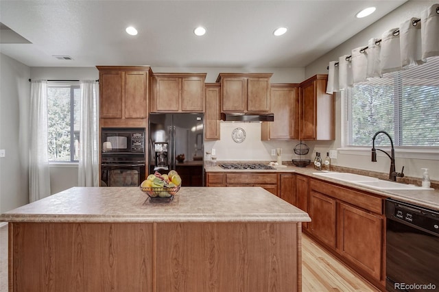 kitchen featuring plenty of natural light, visible vents, a center island, a sink, and black appliances
