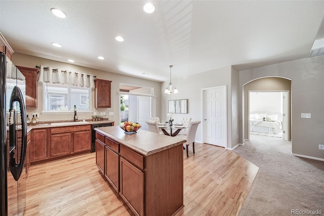 kitchen with a kitchen island, arched walkways, a sink, freestanding refrigerator, and recessed lighting