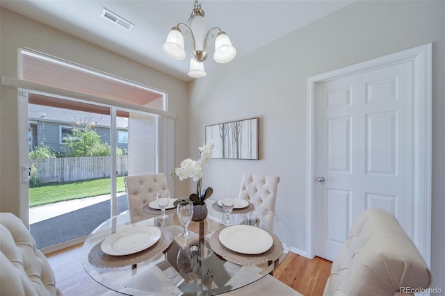 dining space featuring visible vents, wood finished floors, and a chandelier