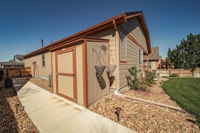 view of side of home featuring an outdoor structure, fence, a gate, a lawn, and a storage shed