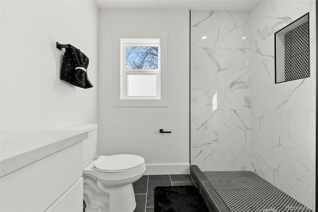 bathroom featuring tile patterned floors, vanity, toilet, and tiled shower