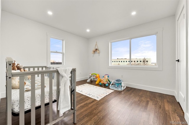 bedroom featuring a nursery area and dark wood-type flooring