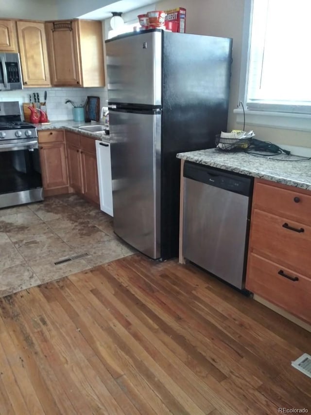 kitchen with visible vents, appliances with stainless steel finishes, light wood-style floors, and a sink