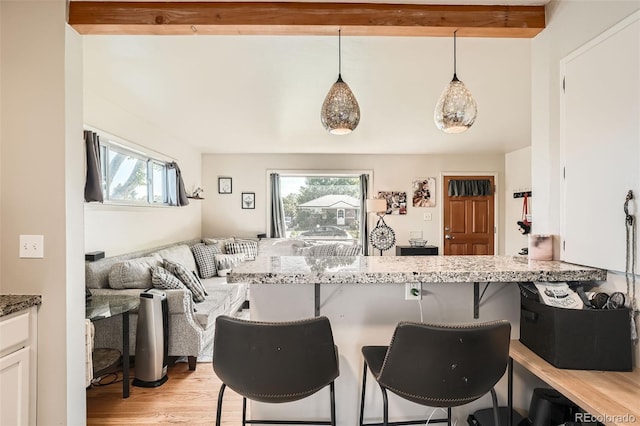 7060 Avrum Dr, Denver, CO 80221 - kitchen featuring plenty of natural light, a kitchen bar, light stone counters, and beam ceiling