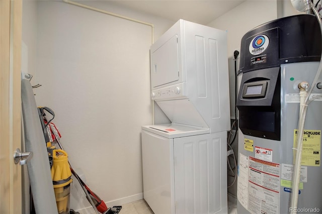 clothes washing area with stacked washer / dryer, baseboards, water heater, laundry area, and light tile patterned floors