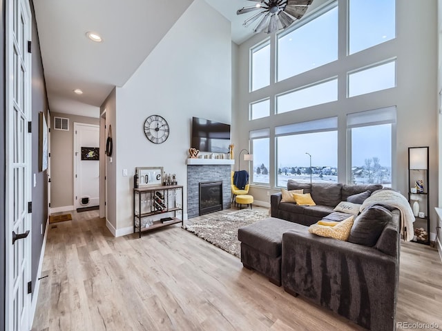 living area featuring baseboards, visible vents, light wood-type flooring, a fireplace, and recessed lighting