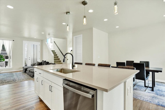 11205 W 53rd Ln, Arvada, CO 80002 - kitchen with stainless steel dishwasher, a sink, light wood-style flooring, open floor plan, and pendant lighting