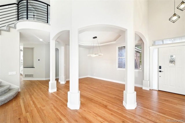 foyer with stairs, light wood-type flooring, and a towering ceiling