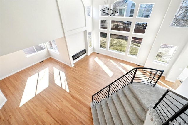 stairway with baseboards, a towering ceiling, and wood finished floors