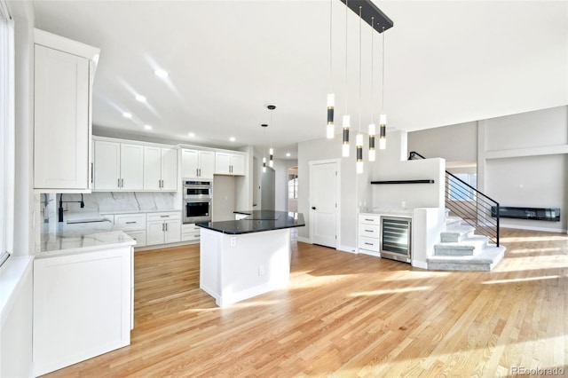 kitchen with wine cooler, light wood-style flooring, backsplash, and a sink