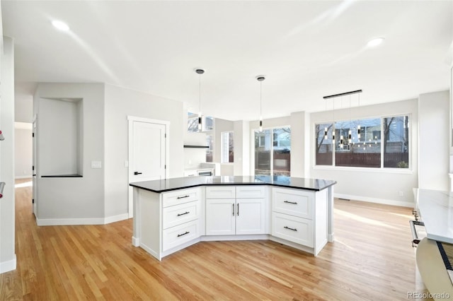 kitchen with baseboards, hanging light fixtures, white cabinets, dark countertops, and light wood-type flooring