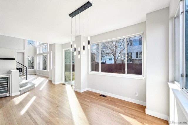 foyer entrance featuring baseboards, stairs, and light wood finished floors