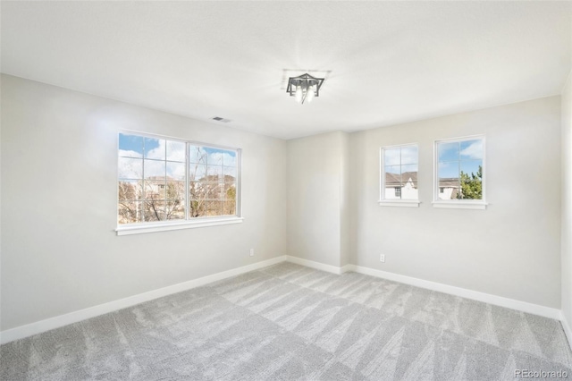 carpeted spare room with visible vents, baseboards, and a healthy amount of sunlight