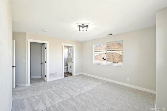 unfurnished bedroom featuring visible vents, baseboards, carpet, and ensuite bathroom