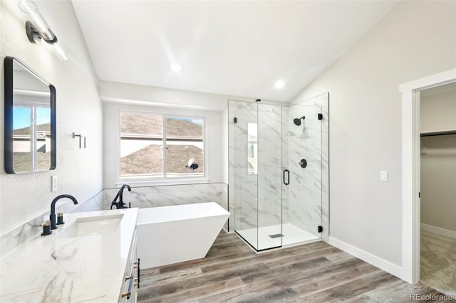 full bathroom with vanity, wood finished floors, a marble finish shower, lofted ceiling, and a soaking tub