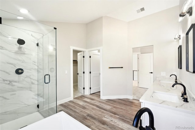 full bathroom with visible vents, a sink, wood finished floors, a marble finish shower, and baseboards