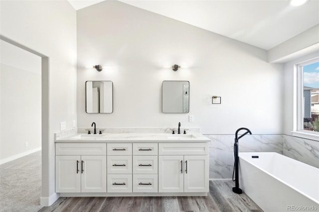 full bath with double vanity, a soaking tub, tile walls, and a sink