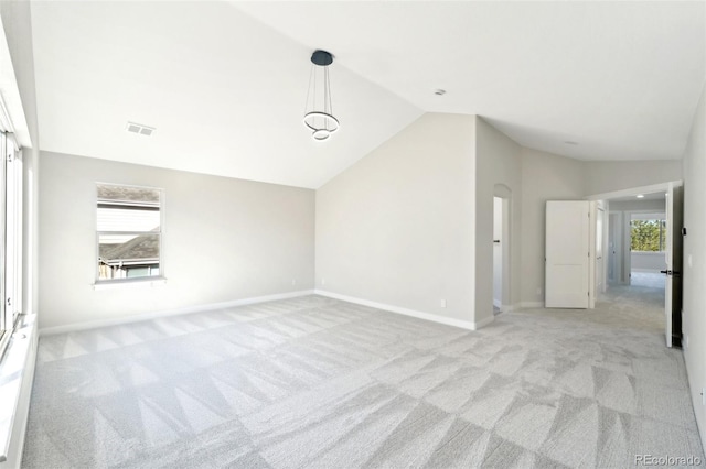 interior space with a wealth of natural light, visible vents, light carpet, and vaulted ceiling