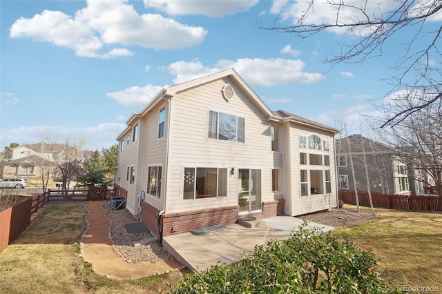 back of property featuring brick siding, a lawn, a patio, and a fenced backyard