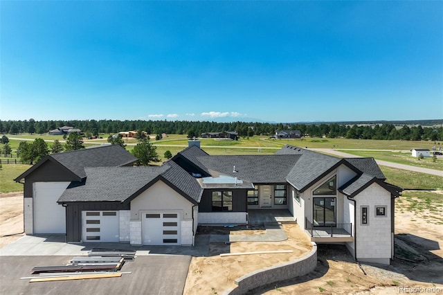 modern farmhouse style home featuring aphalt driveway, a garage, and roof with shingles