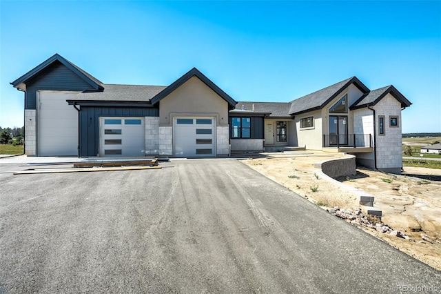 view of front of home with a garage, aphalt driveway, roof with shingles, and stone siding